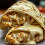 Homemade cheesy garlic chicken wraps with grilled chicken and creamy garlic cheese sauce melting from a toasted tortilla, served fresh and gooey.
