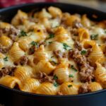 Homemade creamy beef and shells pasta with melted cheese, ground beef, and fresh parsley in a skillet.