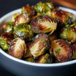 Homemade crispy Brussels sprouts, roasted to golden brown with caramelized edges, halved and topped with fresh parsley in a ceramic bowl.