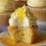 Homemade lemon cupcakes with lemon buttercream, lemon curd drizzle, and a bite showing its soft, fluffy crumb.