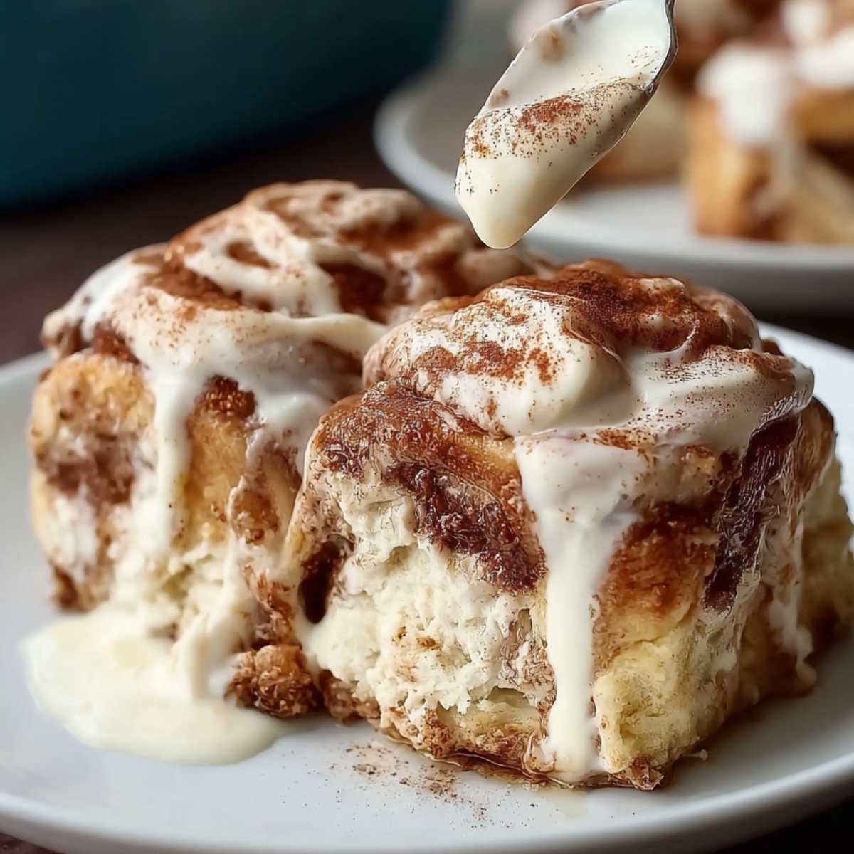 Best Tres Leches Cinnamon Rolls topped with whipped cream and cinnamon, served with a fork on a white plate.