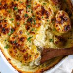 Homemade Creamy Au Gratin Potatoes in a white casserole dish with parsley garnish.