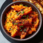 Homemade Smashed Carrotswde on a rustic plate, golden orange with crispy edges, sprinkled with sea salt and fresh herbs, glistening with olive oil in warm natural light.