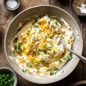 Bowl of creamy jalapeño popper filling with cream cheese, cheddar, green onions, and pepper.