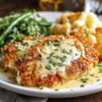 Longhorn Steakhouse Parmesan Chicken topped with melted cheese and parsley, served with green beans and roasted potatoes on a white plate.