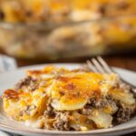 Hamburger Potato Casserole sits on a plate, layered with tender potatoes, browned beef, and golden melted cheese.