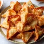 A plate of golden, crispy crab rangoons with perfectly browned edges, arranged neatly.