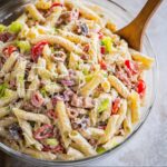 Homemade Italian Grinder Pasta Salad with spiral pasta, tomatoes, lettuce, and bacon, topped with Parmesan and creamy dressing.