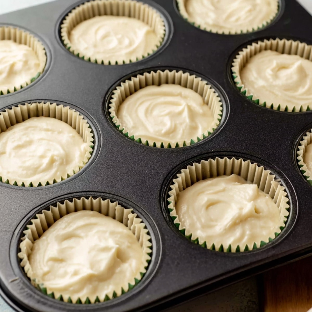 Mini margarita cheesecakes in muffin cups, with the creamy filling just before baking, showing a smooth surface.