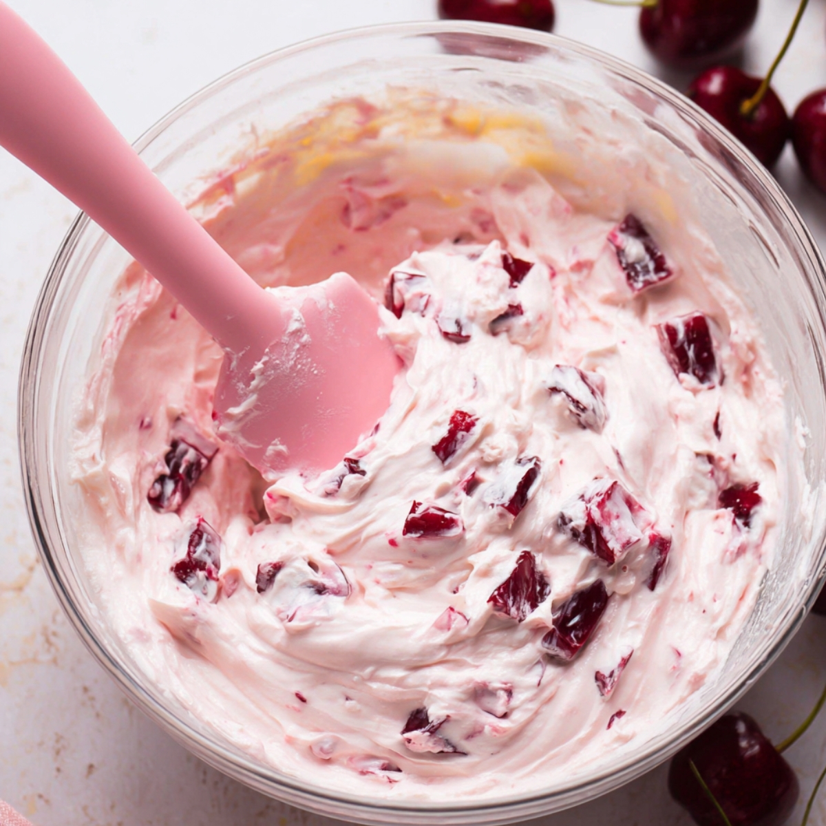 In a chilled bowl, whip the heavy cream with a mixer until stiff peaks form. Set it aside. In another large bowl, beat the mascarpone, sugar, ½ cup of the cherry syrup, Amaretto, vanilla, and almond extract until the mixture is smooth and well combined, about 2 minutes. Gently fold in 1 cup of the whipped cream to lighten the mascarpone mixture, then fold in the rest of the whipped cream until everything is just incorporated. Stir in the chopped cherries.