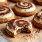 Tiramisu Cookies with a swirl of mascarpone cream and cocoa powder, with a bite taken out.