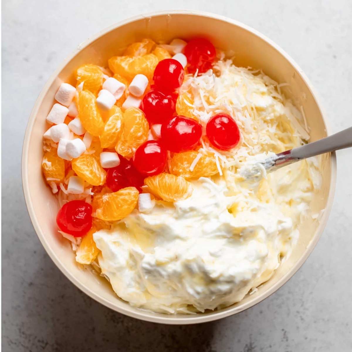 Drain your canned fruits really, really well. Pat them dry with a paper towel if you need to. Then add all your fruit, coconut, cherries, and marshmallows to a large serving bowl.