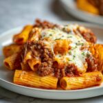 Slice of Baked Ziti with Ground Beef, marinara sauce, and melted mozzarella cheese served on a white plate