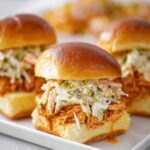 A plate of Buffalo Chicken Sliders topped with creamy coleslaw.