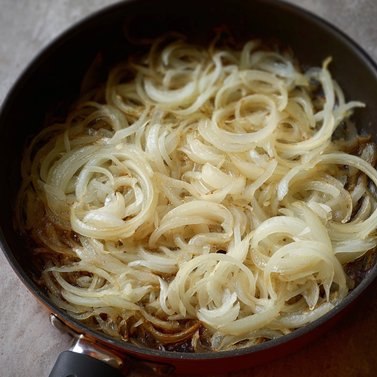 Onions slowly caramelizing in a pan, turning golden and sweet, ready to be added to dishes.