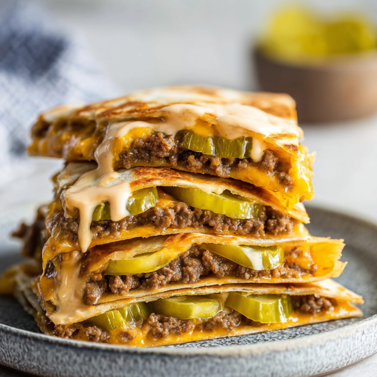 Cheeseburger Quesadillas with melted cheese, ground beef, pickles, and special sauce, served on a plate.