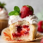 Homemade Strawberry Shortcake Cupcakes filled with strawberry compote and topped with whipped cream, strawberry, and mint