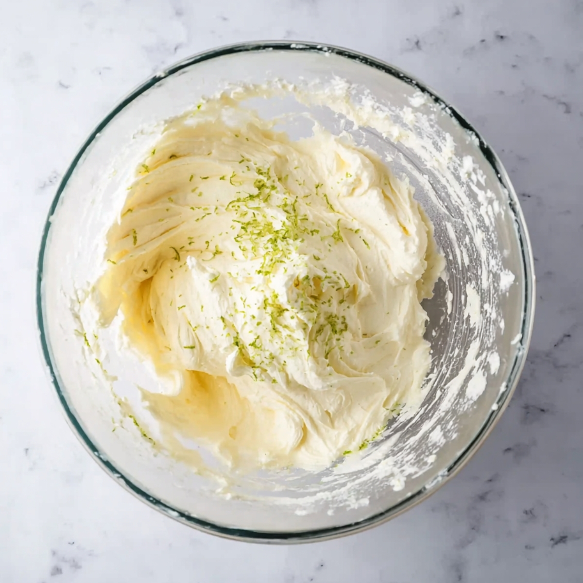 A glass bowl with smooth lime frosting, topped with lime zest.