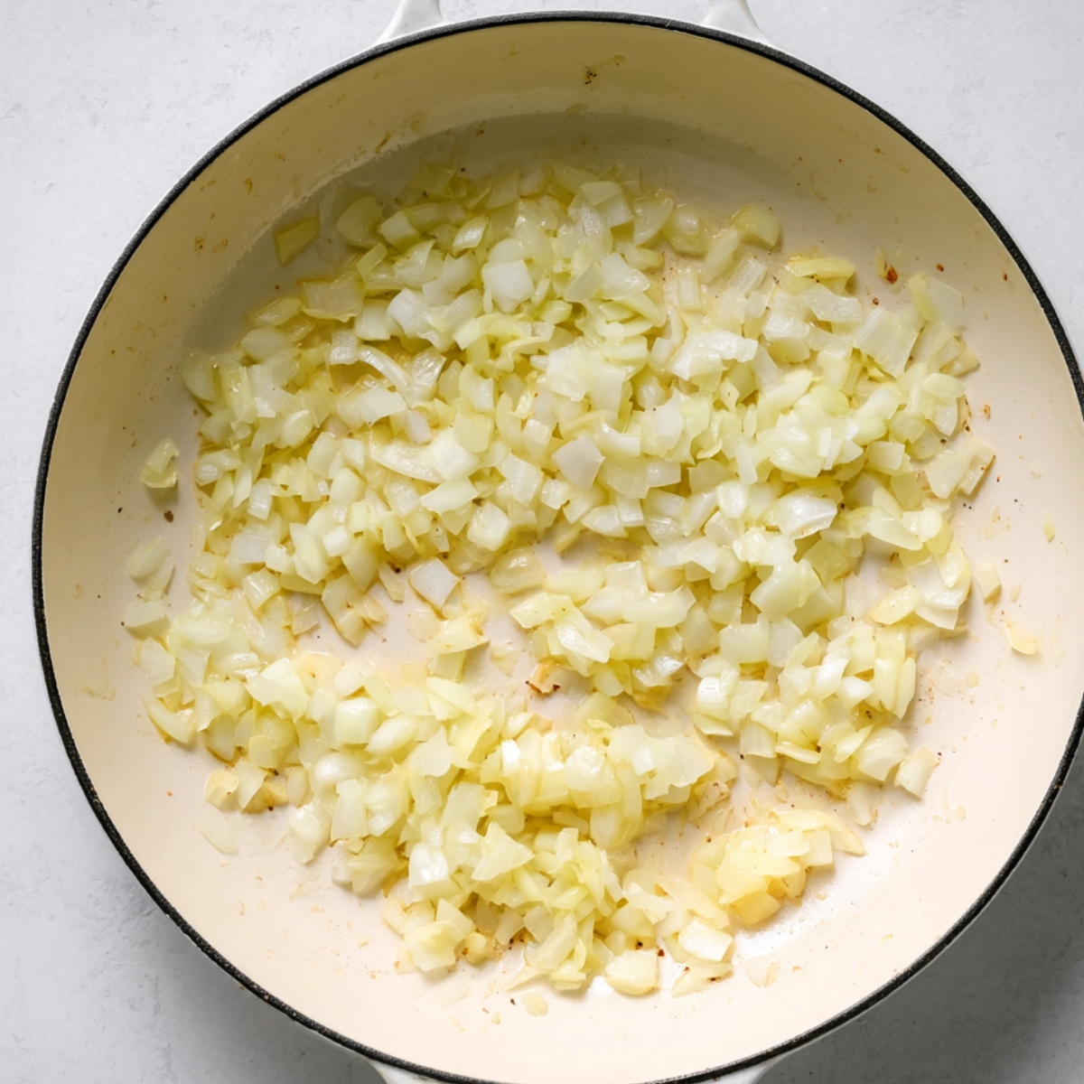 Chopped onions sautéing in a large skillet until soft and translucent