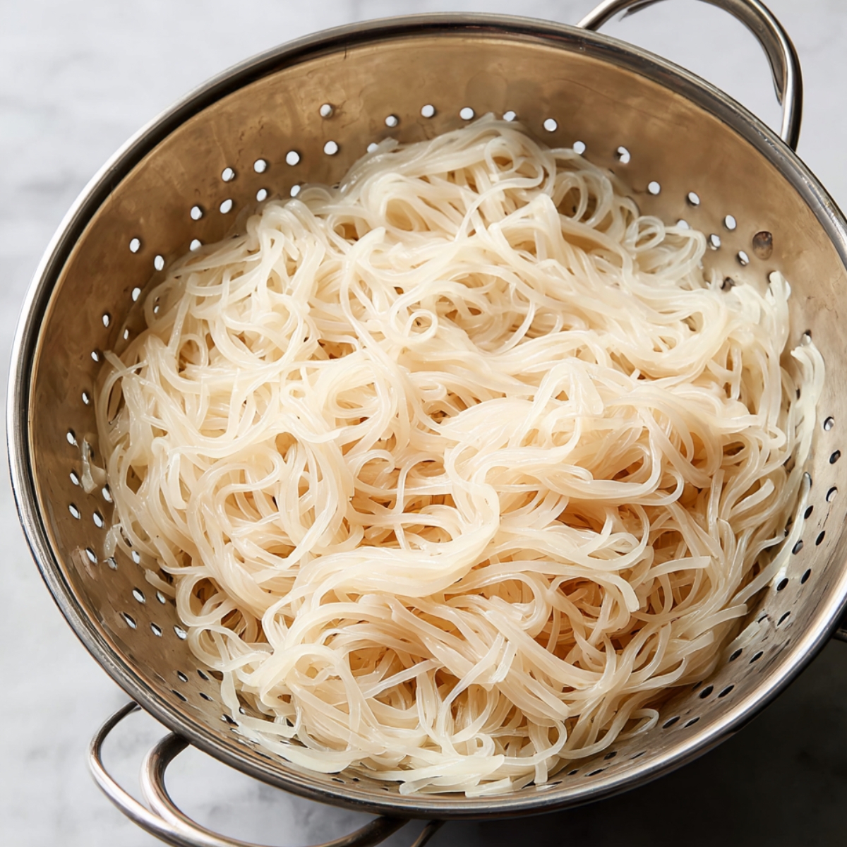 Rice noodles drained in a colander, ready to be tossed with a flavorful sauce or stir-fry.