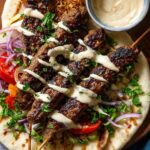 Delicious grilled kofta kebabs served on warm flatbread, drizzled with a creamy tahini sauce, and garnished with fresh herbs, red onions, and tomatoes.