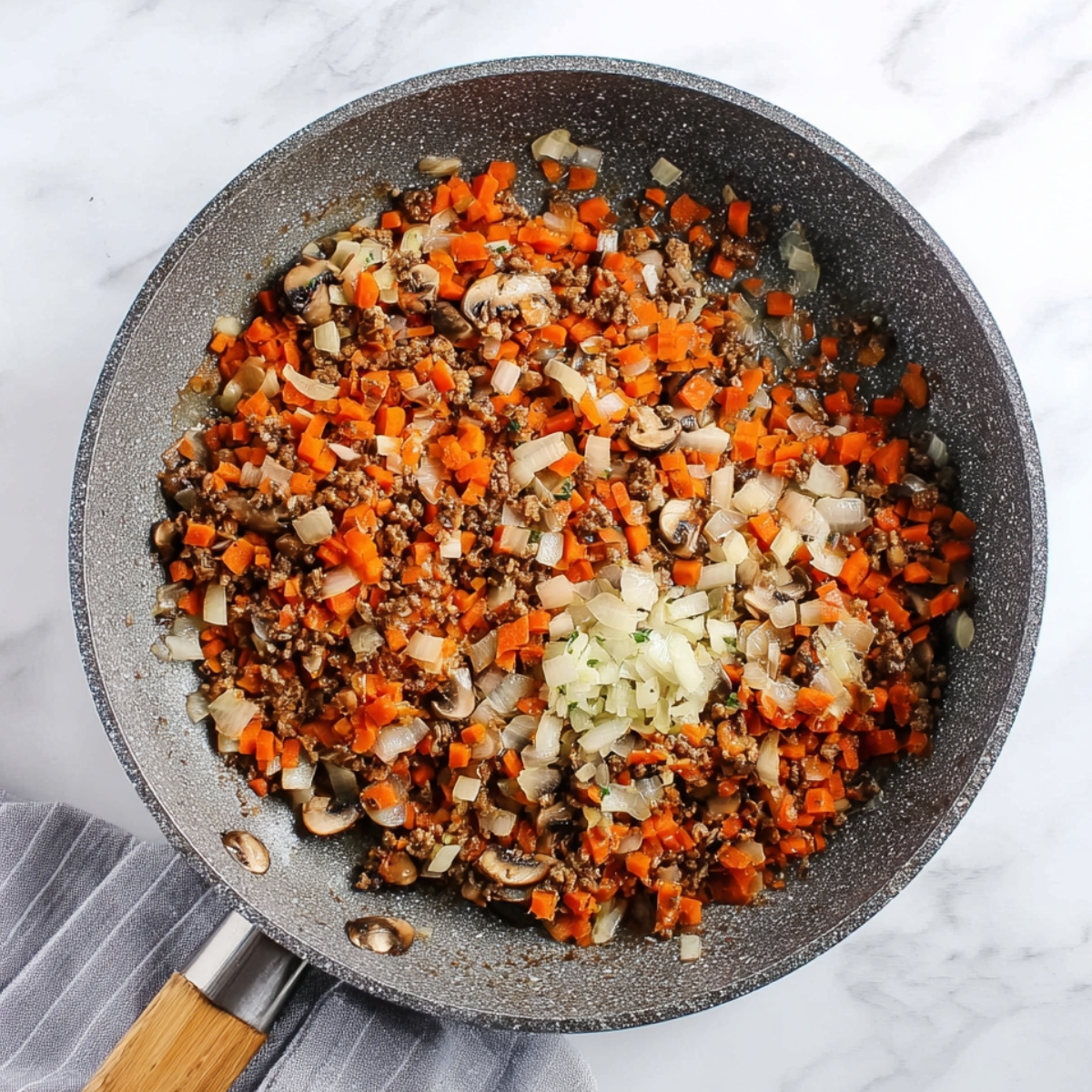 Sautéed carrots, mushrooms, and onions in a pan, ready to be added to the lentil loaf mixture.