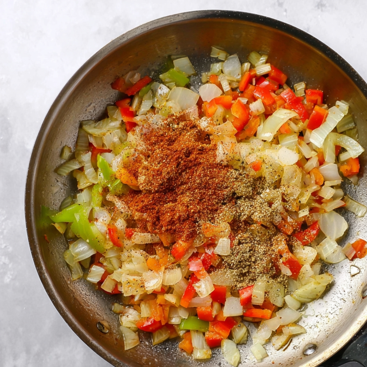 A skillet containing sautéed onions, peppers, and celery along with taco seasoning for making quesadillas.